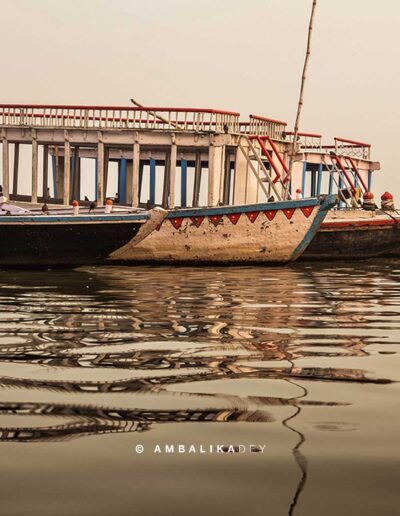 Wooden boats moored on the Ganges at Assi Ghat in Varanasi with reflections on the water