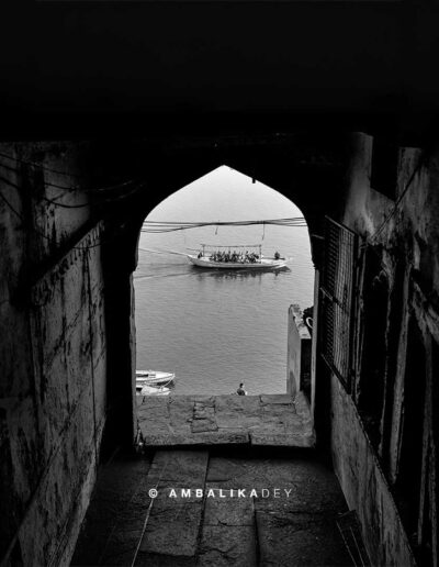 Passenger boat on the Ganges framed through a dark arched passage in Varanasi